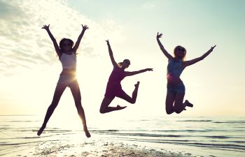 three happy young women jumping high on the beach